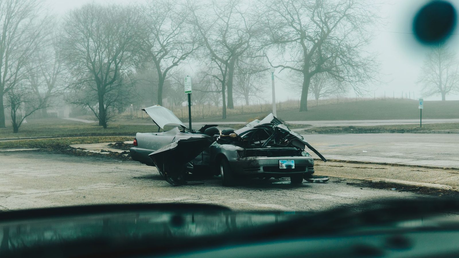 Auto gravemente dañado en calle deserta durante mañana con niebla en Chicago.