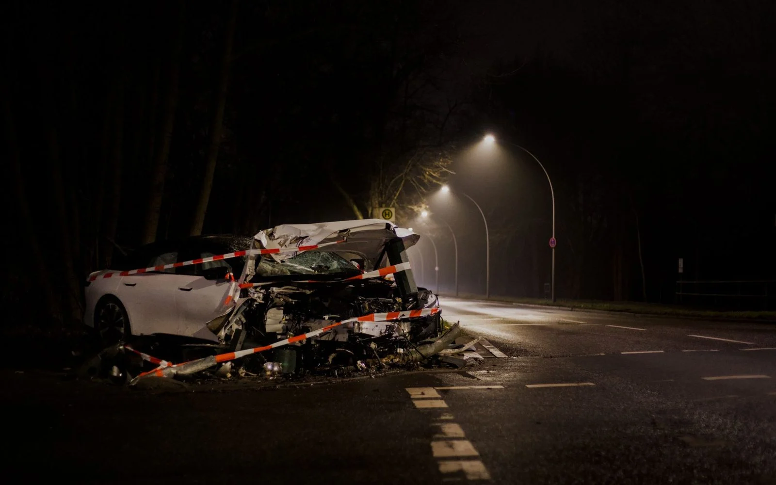 Automóvil destrozado tras accidente en calle oscura por la noche.