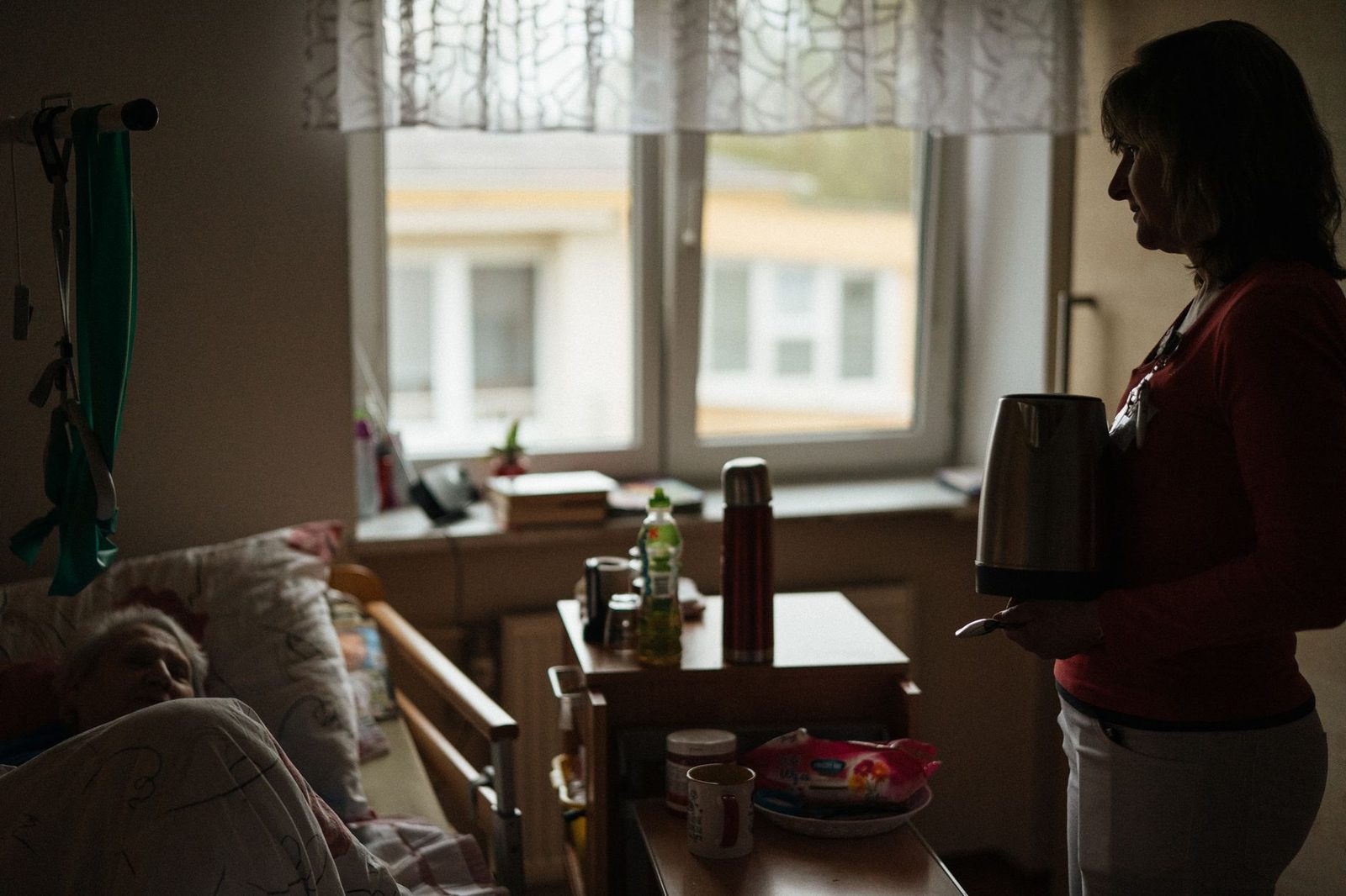 Caregiver serving a warm beverage to a senior resident in a retirement home.