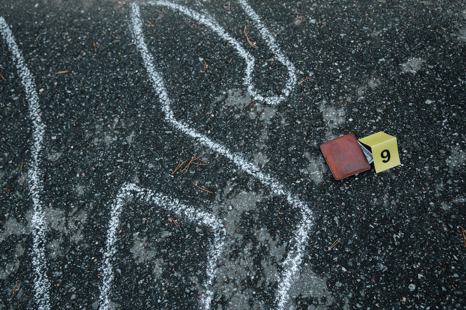 Chalk outline and evidence markers on asphalt street.