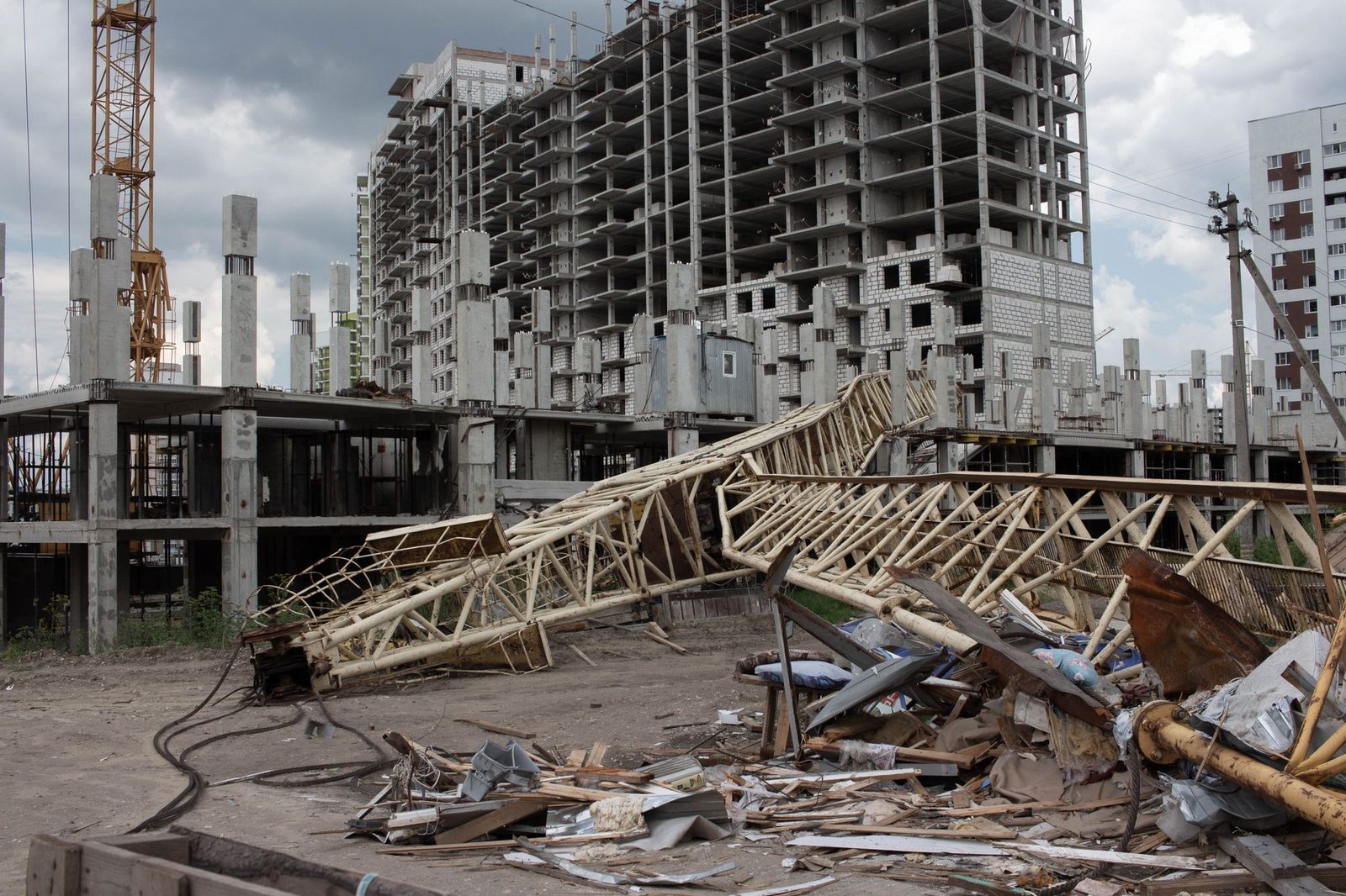 Collapsed crane at urban construction site with unfinished buildings.