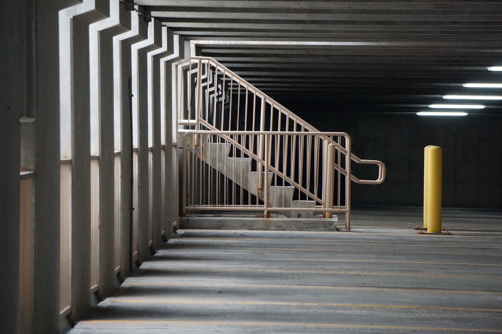 Concrete staircase with railings in empty parking garage.