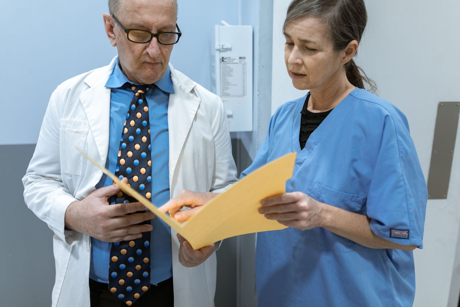 Doctor and nurse reviewing patient medical records in clinical setting.
