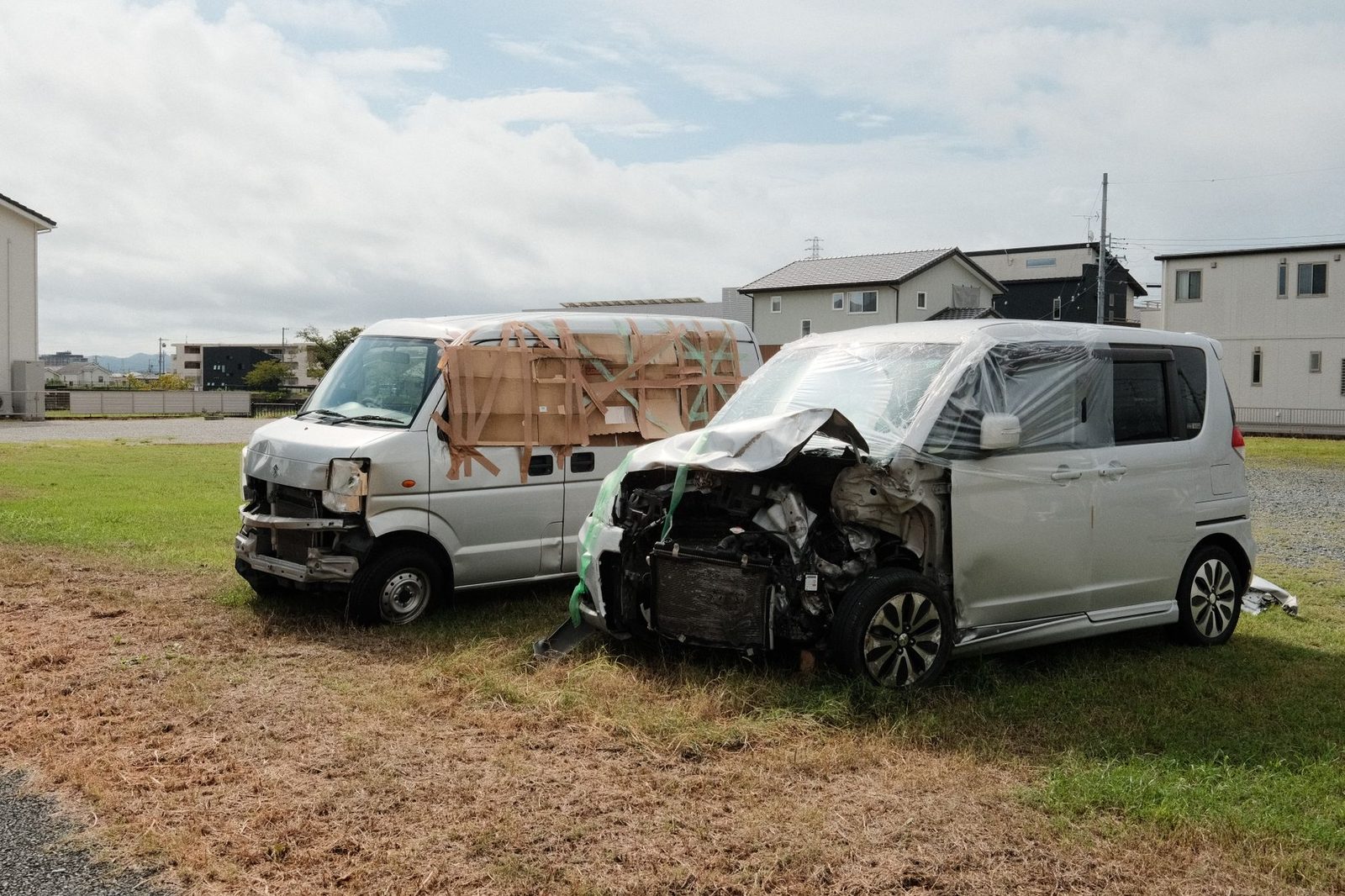 Dos furgonetas destrozadas en un área con pasto tras accidente vehicular.