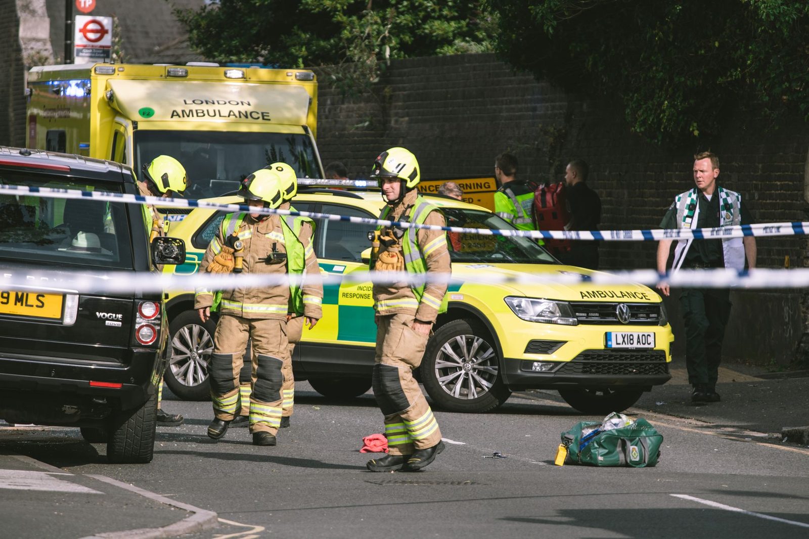 Emergency responders and vehicles at a street accident scene with police tape.