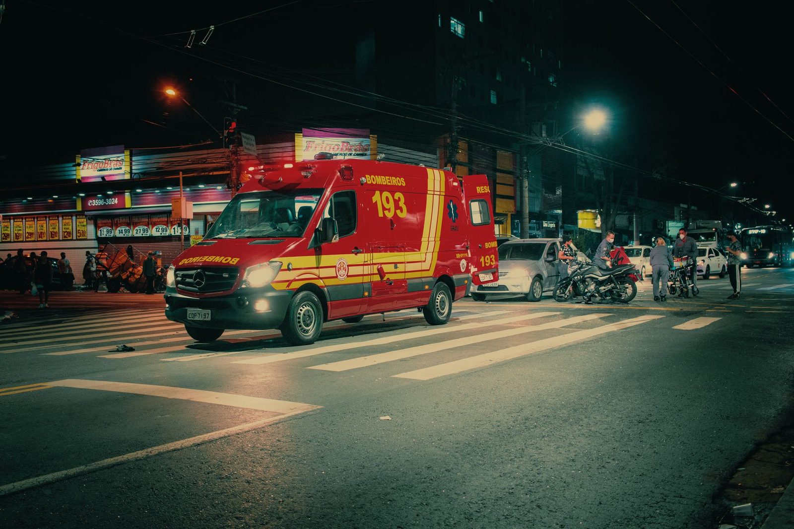 Emergency vehicle at nighttime car crash scene on city street.