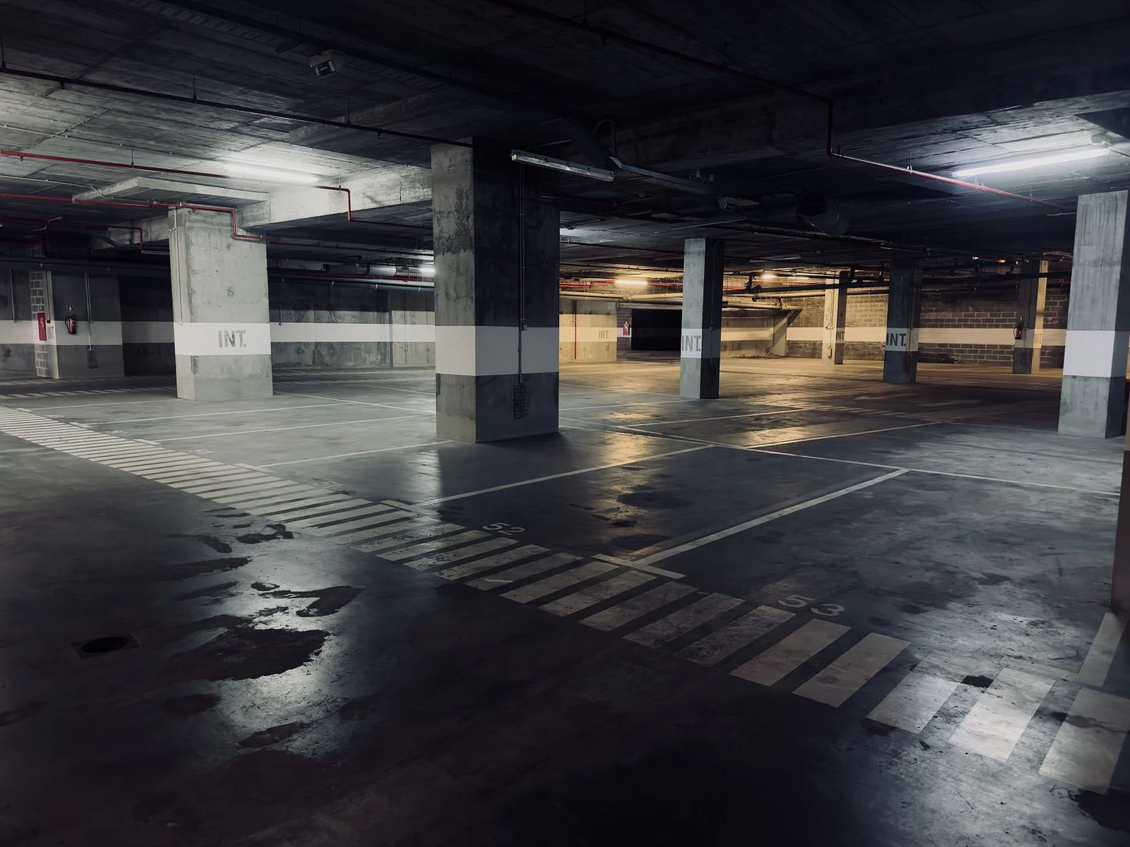 Empty parking garage with puddles on wet floor.