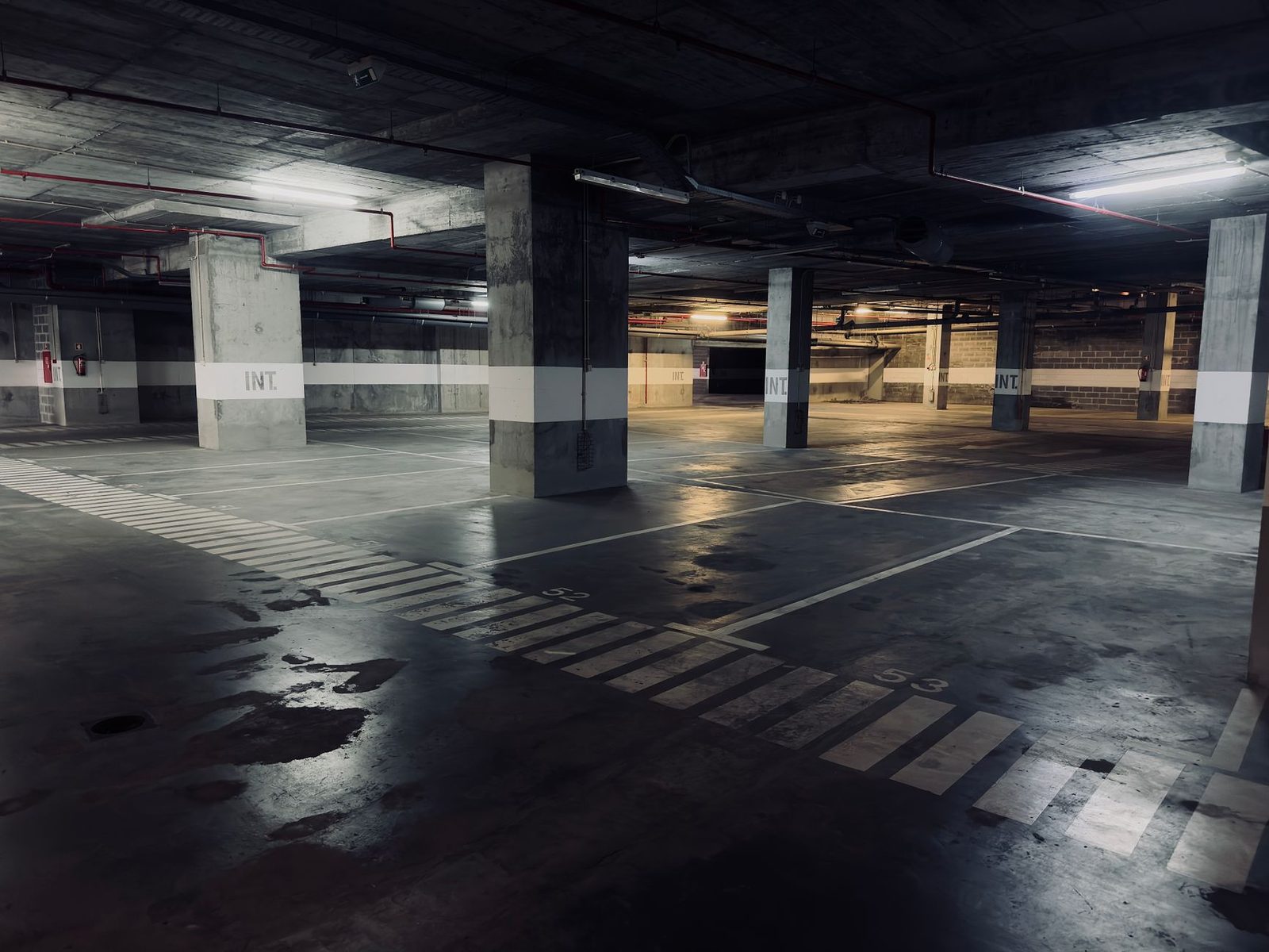 Garaje de estacionamiento subterráneo vacío con charcos en el piso.