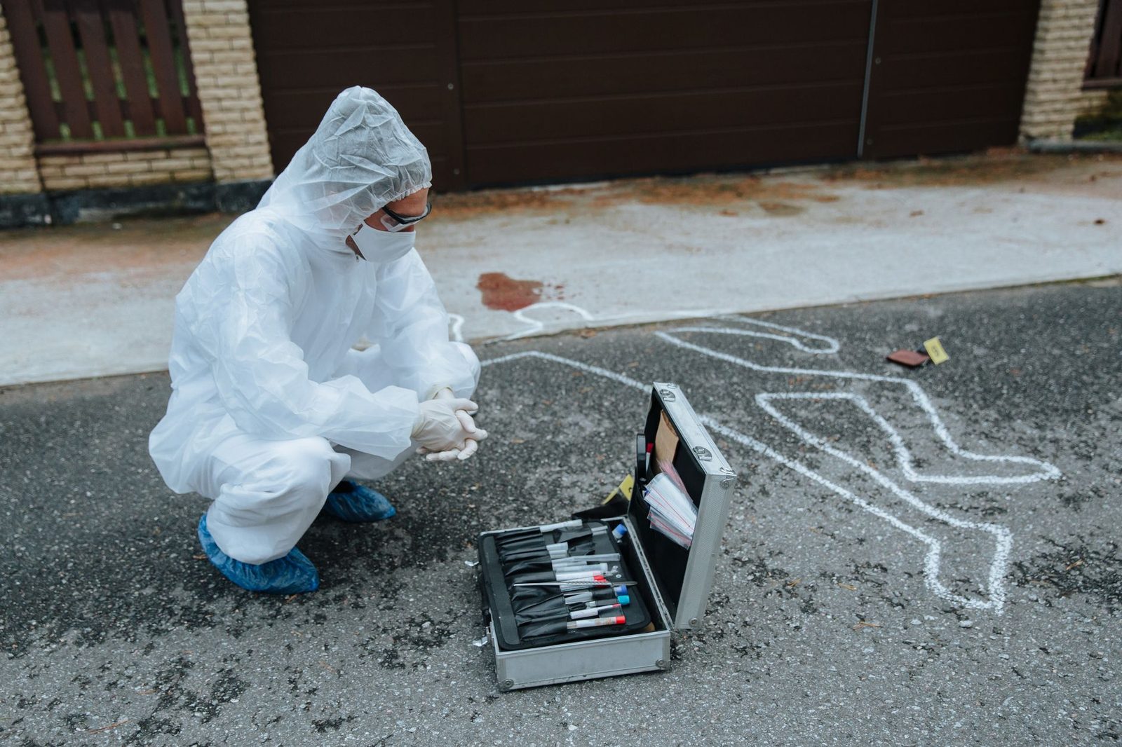 Investigador forense en equipo de protección examinando evidencia en escena del crimen.