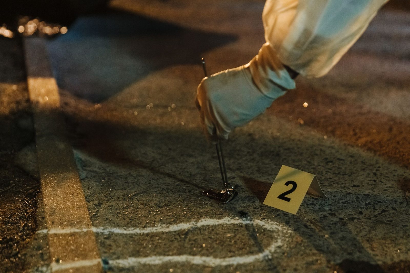 Investigador forense recolectando evidencia en escena de crimen nocturna con guantes.