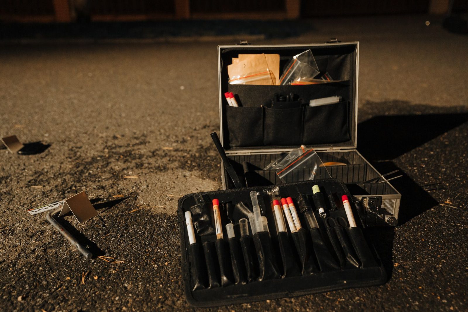Kit de evidencia forense en carretera durante investigación nocturna de escena del crimen.