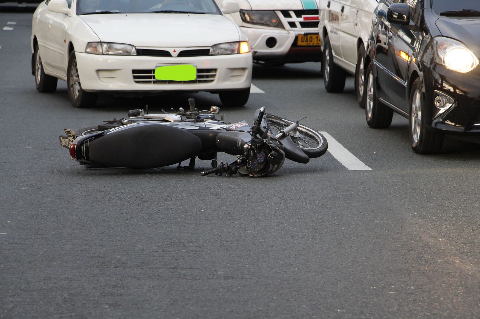 Motorcycle crashed on city street with traffic in background.
