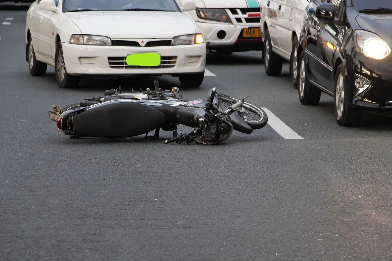 Motocicleta volcada en una calle urbana tras un accidente, con tráfico al fondo.