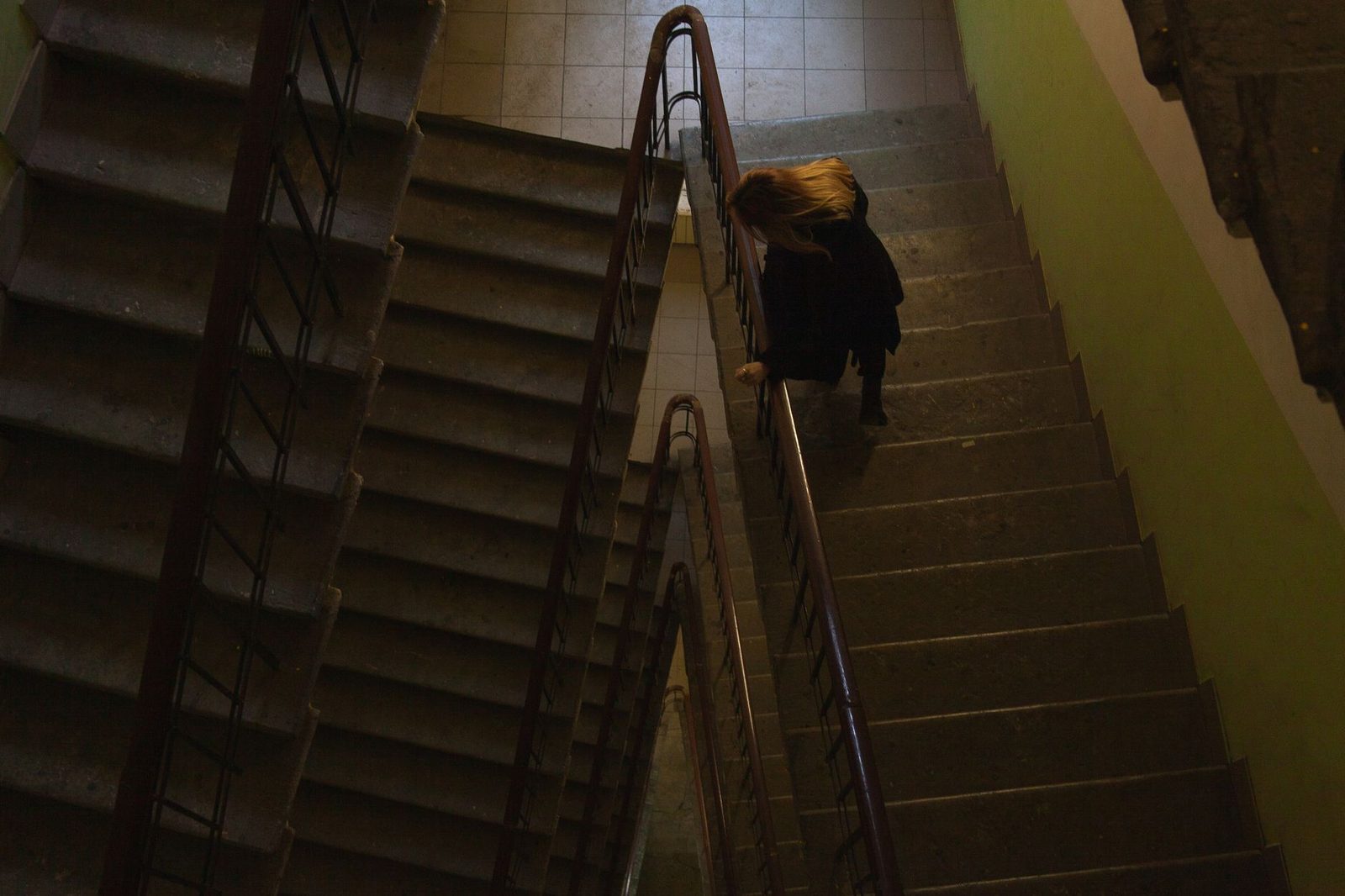 Mujer caminando por escaleras mal iluminadas en un edificio.
