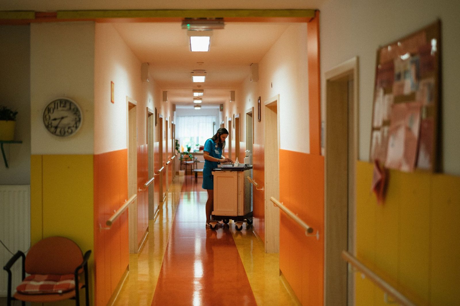 Nurse walking through a bright hospital hallway with colorful walls.