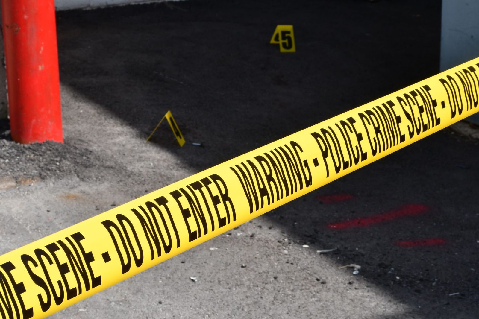 Police crime scene tape cordoning off a concrete street area.