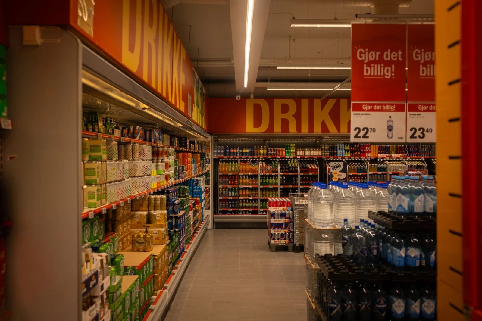 Supermarket beverage aisle with promotional signage and colorful product displays.