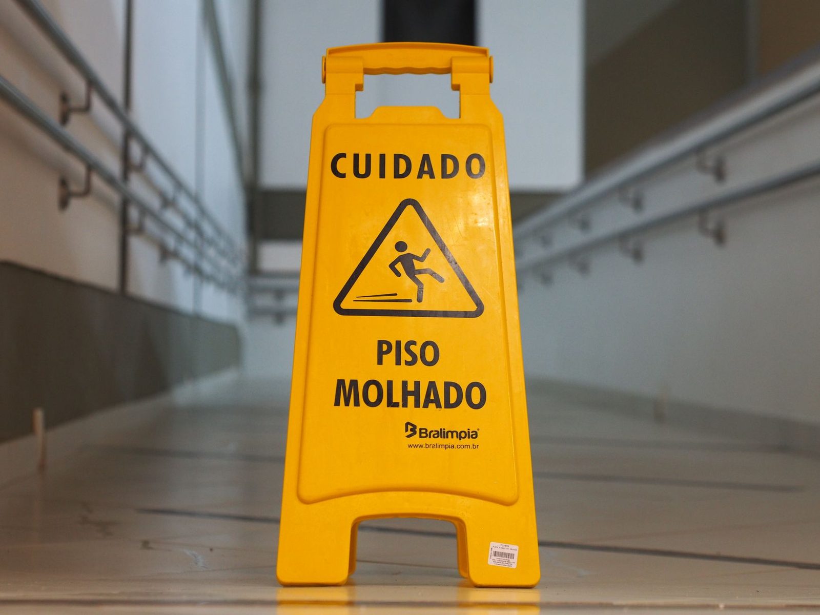 Yellow wet floor caution sign in a hotel corridor with tiled flooring.