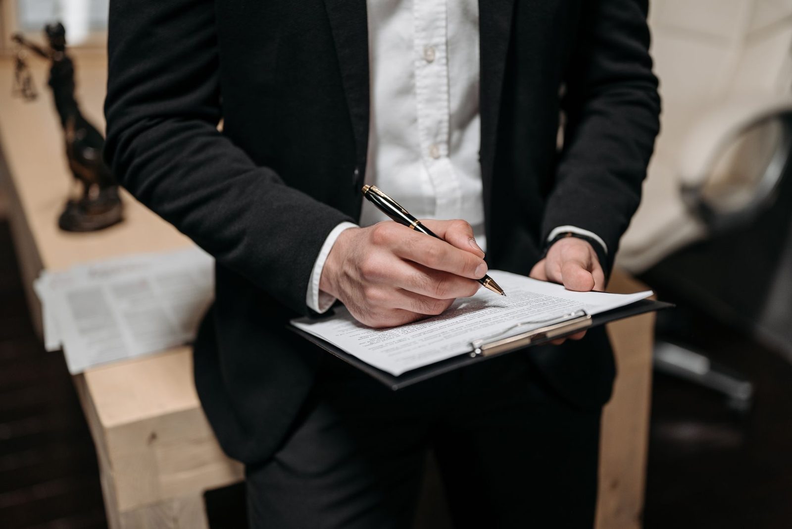 Profesional firmando un contrato sobre un portapapeles en un escritorio.