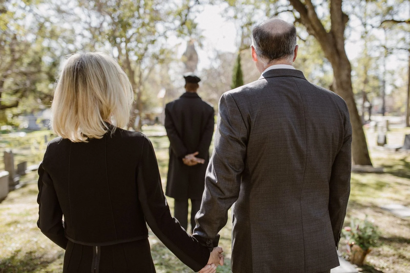 A couple holds hands at a cemetery during a memorial service.