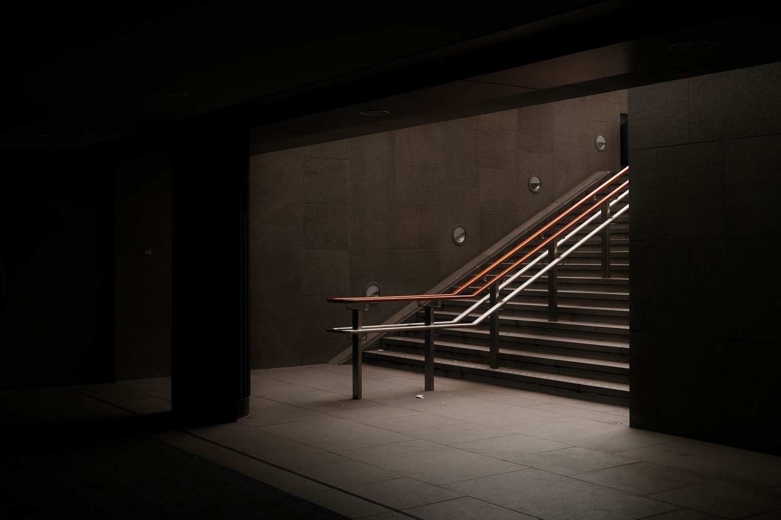 A dimly lit underground staircase with minimalist, moody lighting.