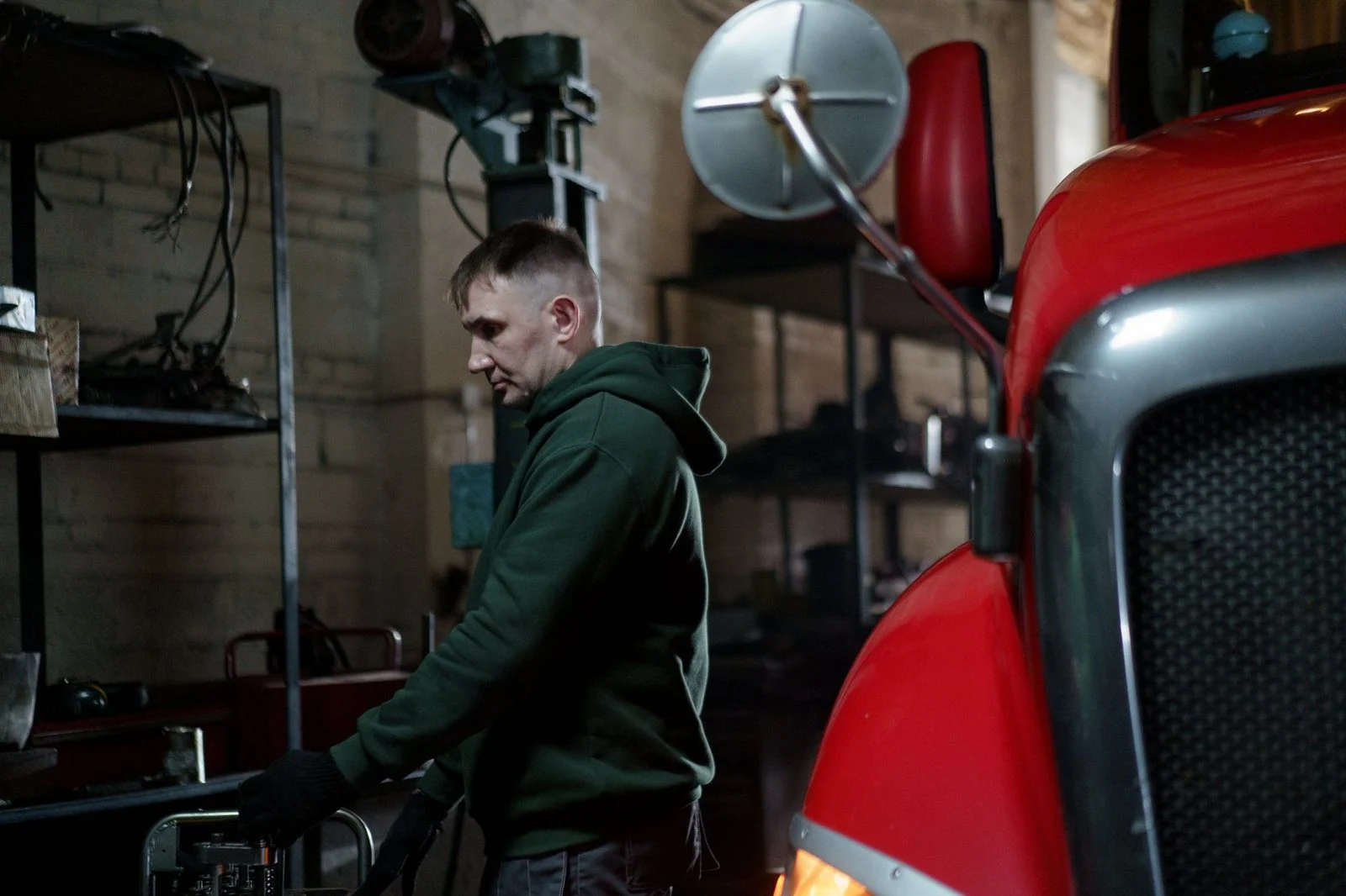 Un mecánico inspecciona una camioneta roja en un taller.