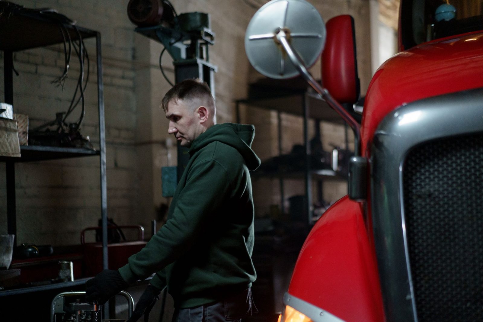 A mechanic in a garage inspects a red truck.