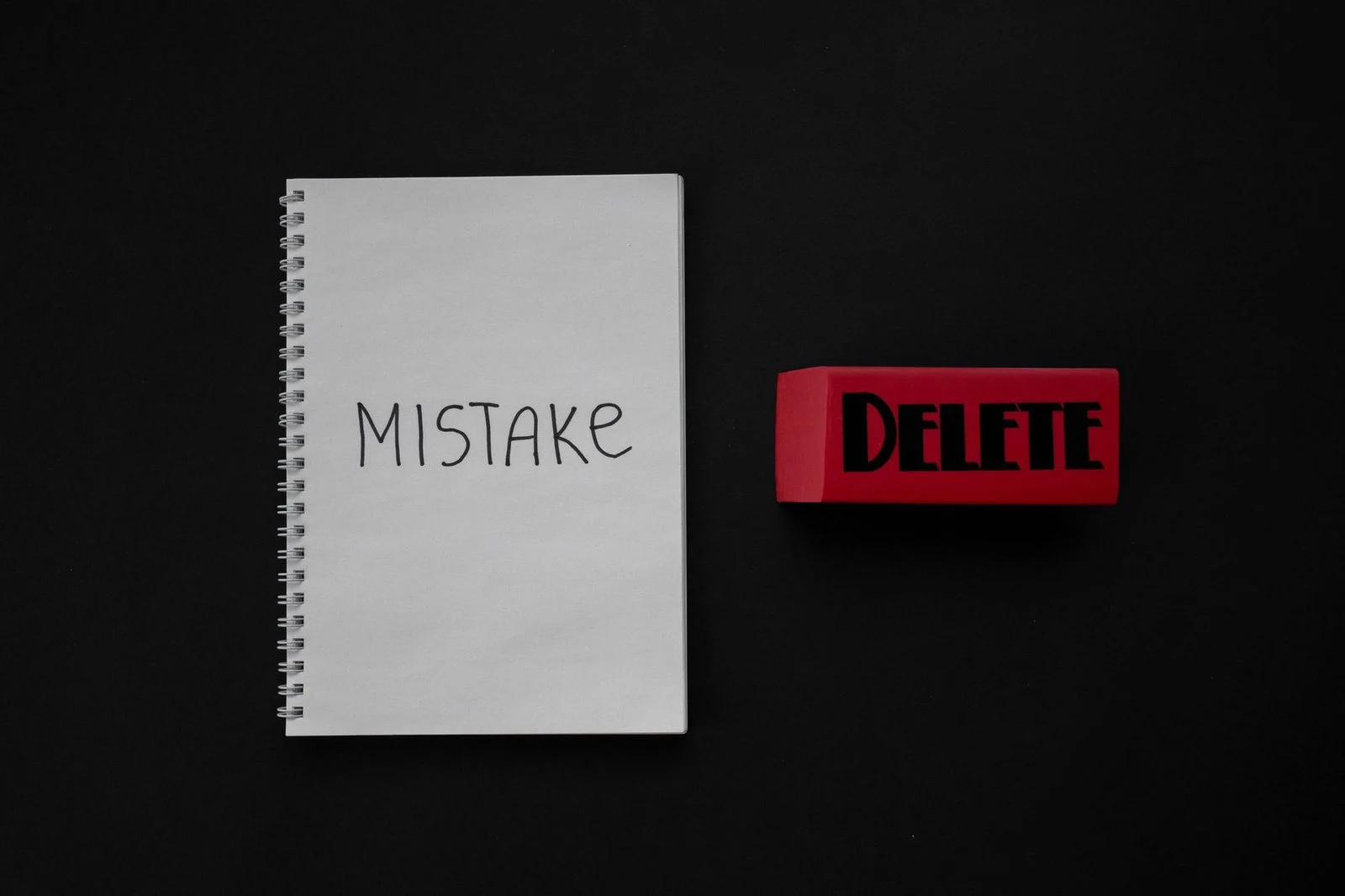 A notebook labeled "Mistake" sits beside a red eraser on a dark background.