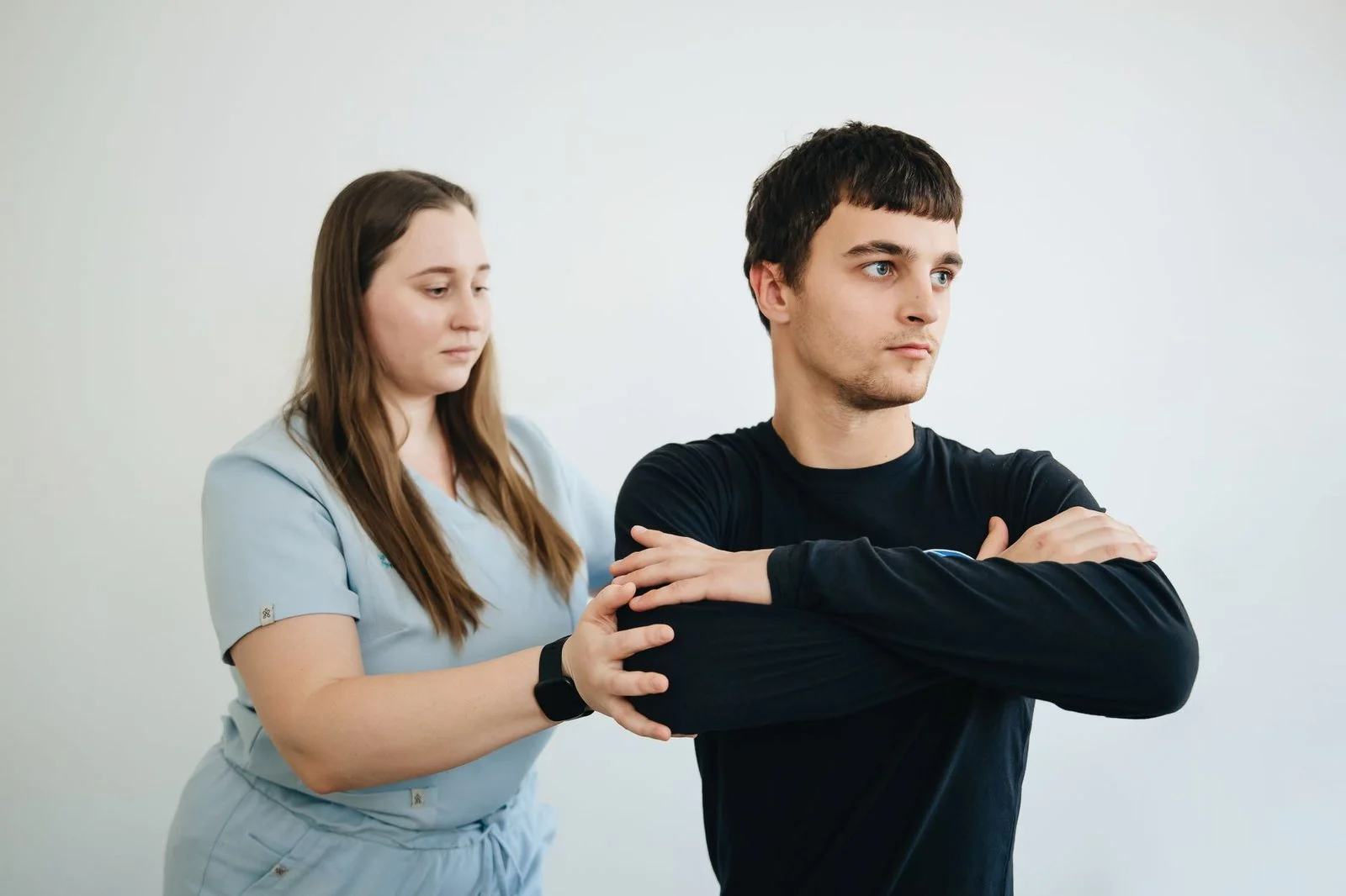 A physiotherapist helps a patient perform arm exercises in a clinic.