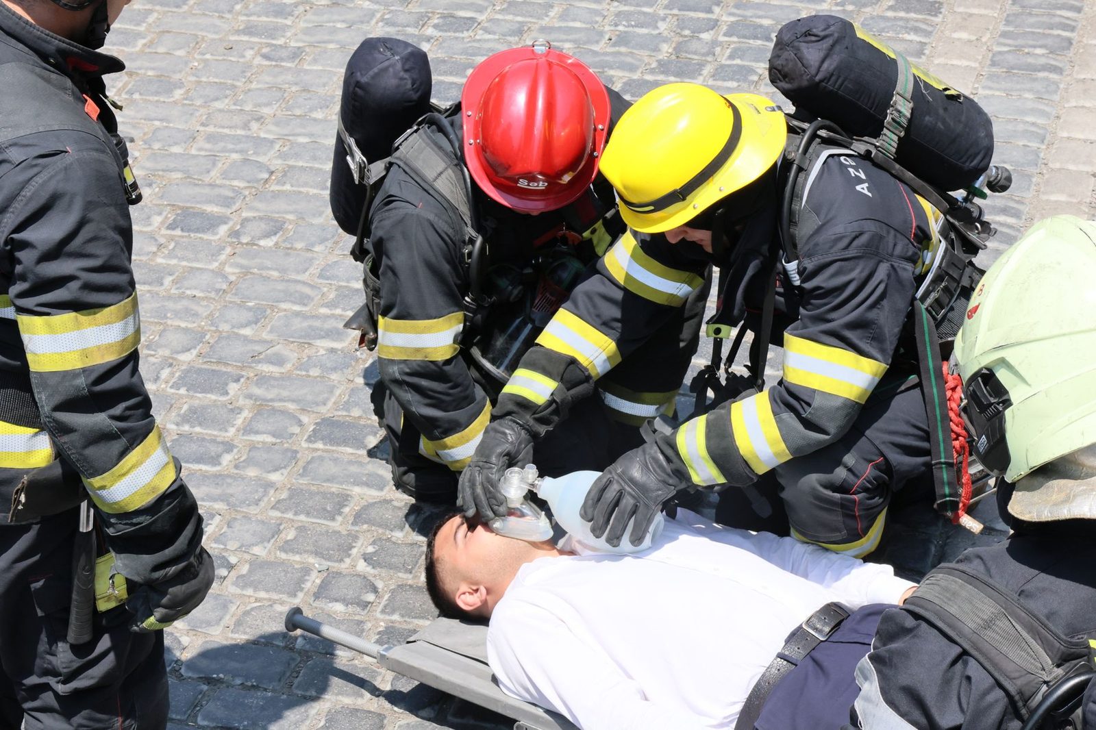 Bomberos realizan RCP a un hombre lesionado en la calle con mascarilla de ventilación.