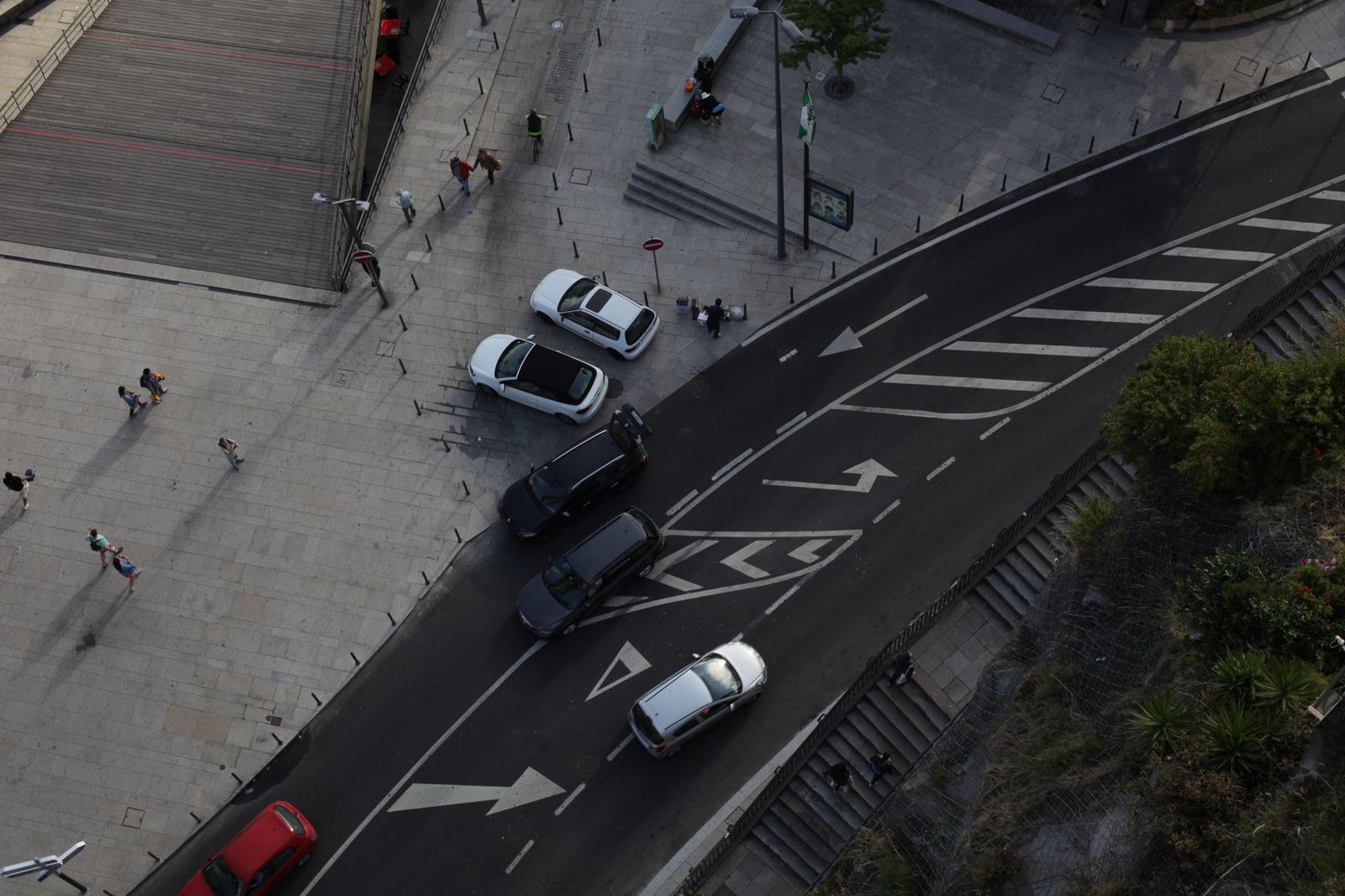 Calle urbana con autos y peatones vistos desde arriba.