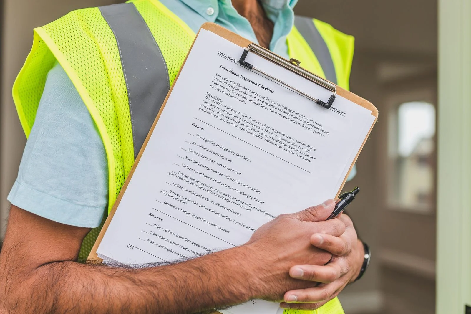 Close-up of a home inspector holding a checklist on a clipboard with a pen.