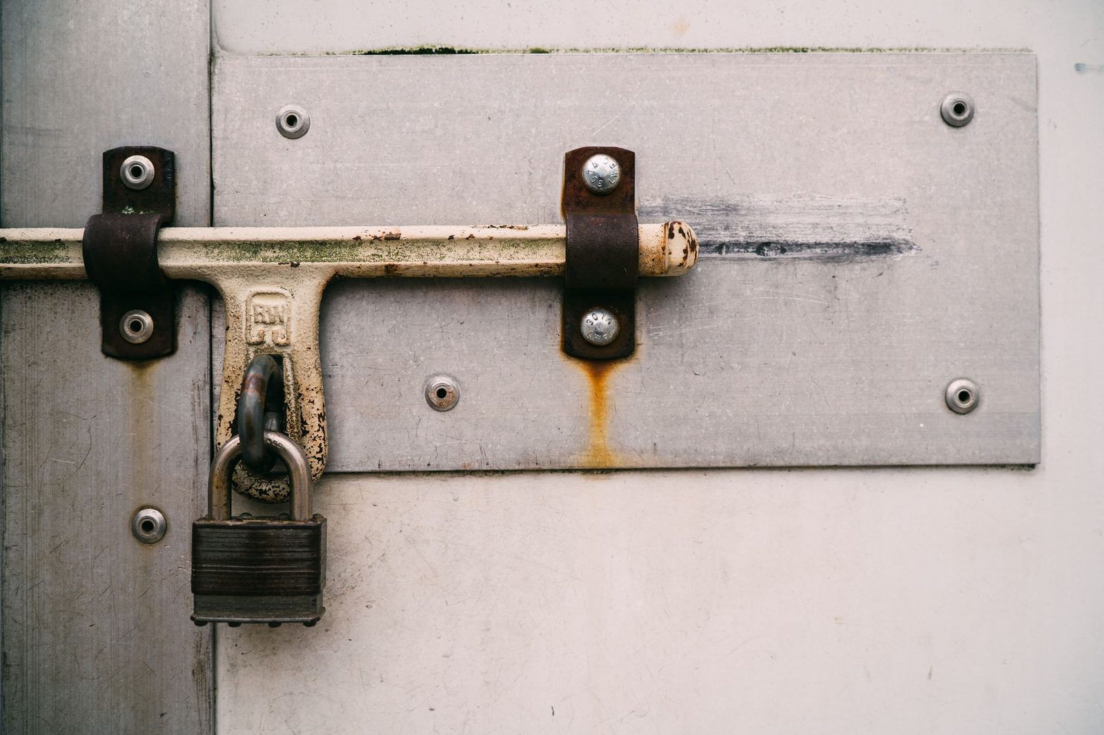 Close-up of a rusty padlock securing a metal door.