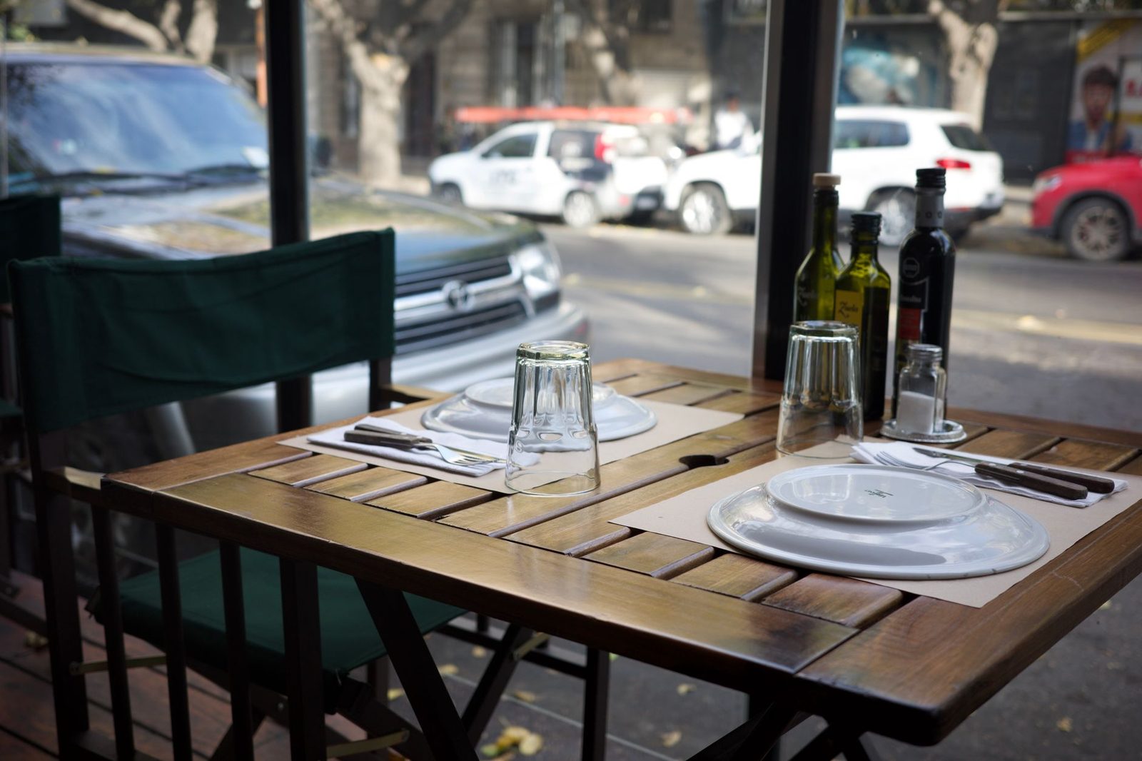 Comedor exterior de restaurante con botellas de vino y platos servidos.