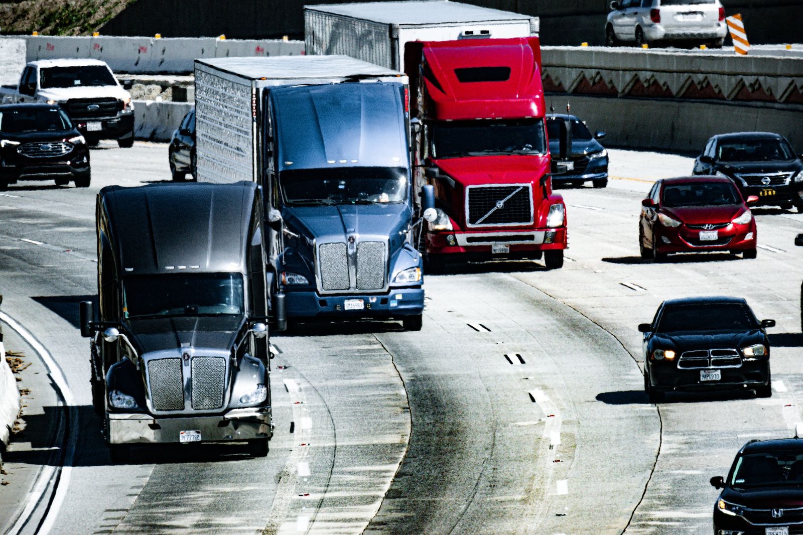 Trucks and cars moving along a busy city highway during the daytime.