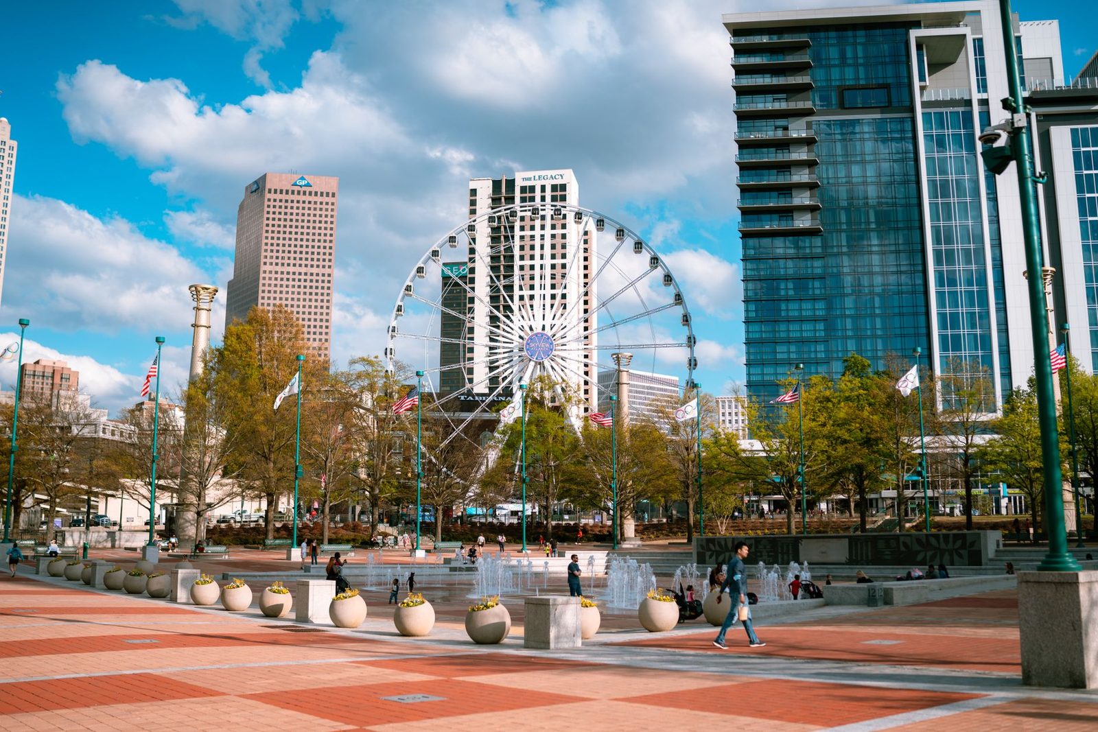 Downtown Atlanta skyline with skyscrapers and a Ferris wheel rising above Centennial Olympic Park on a sunny day.