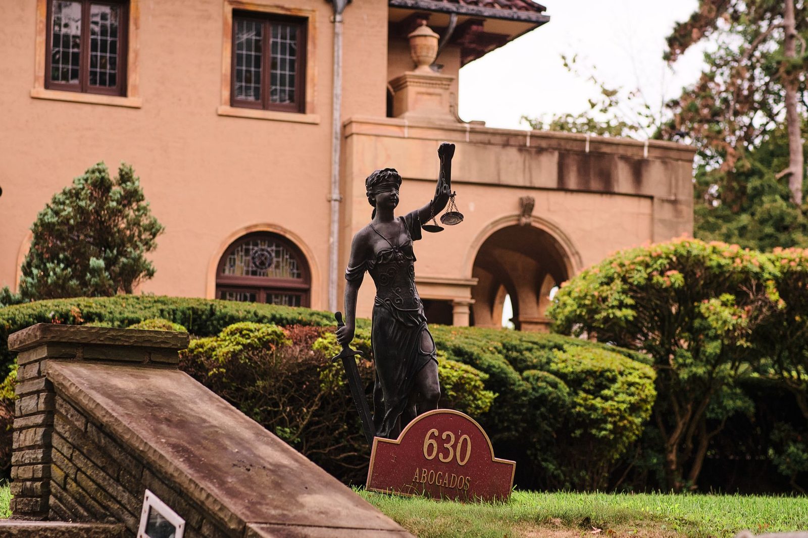 Estatua de la Justicia frente a mansión con jardín en Arizona.