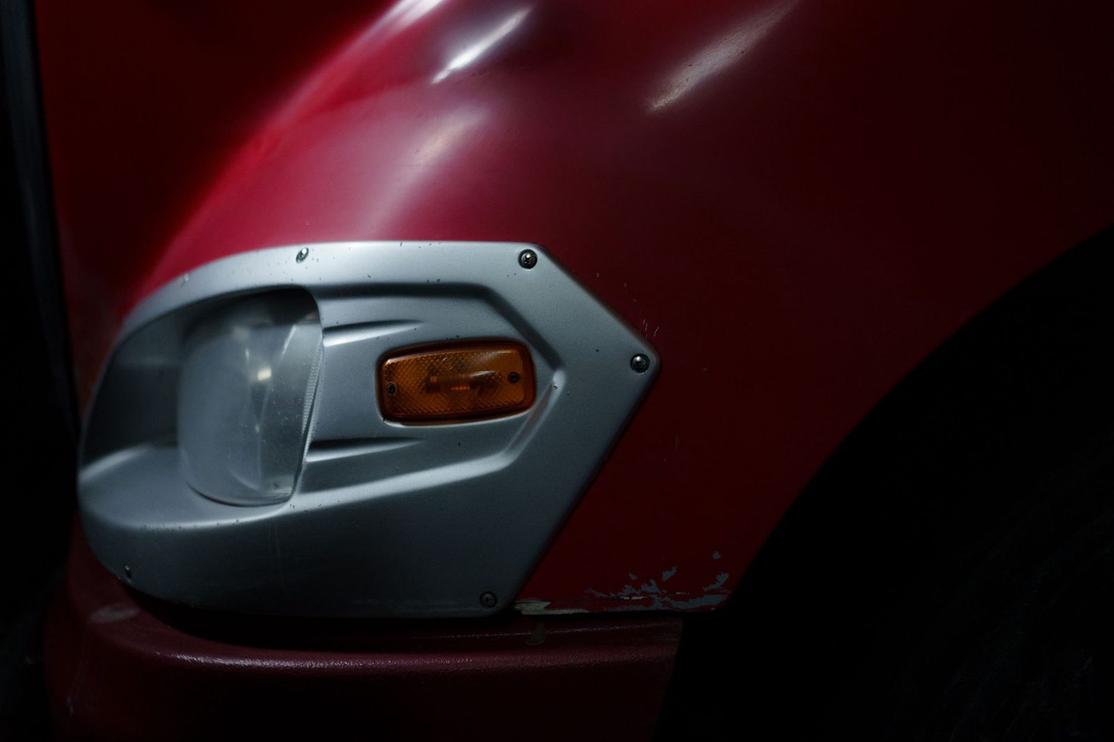 Faro rojo de vehículo con detalles cromados en garaje.