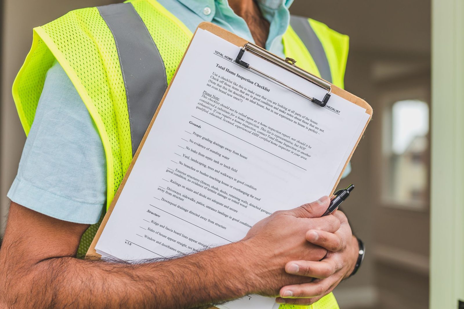 Home inspector holding clipboard with checklist and pen.