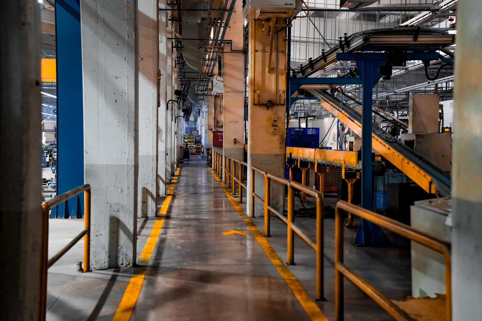 Vista amplia del interior de una fábrica moderna con maquinaria industrial y sistemas de transporte.