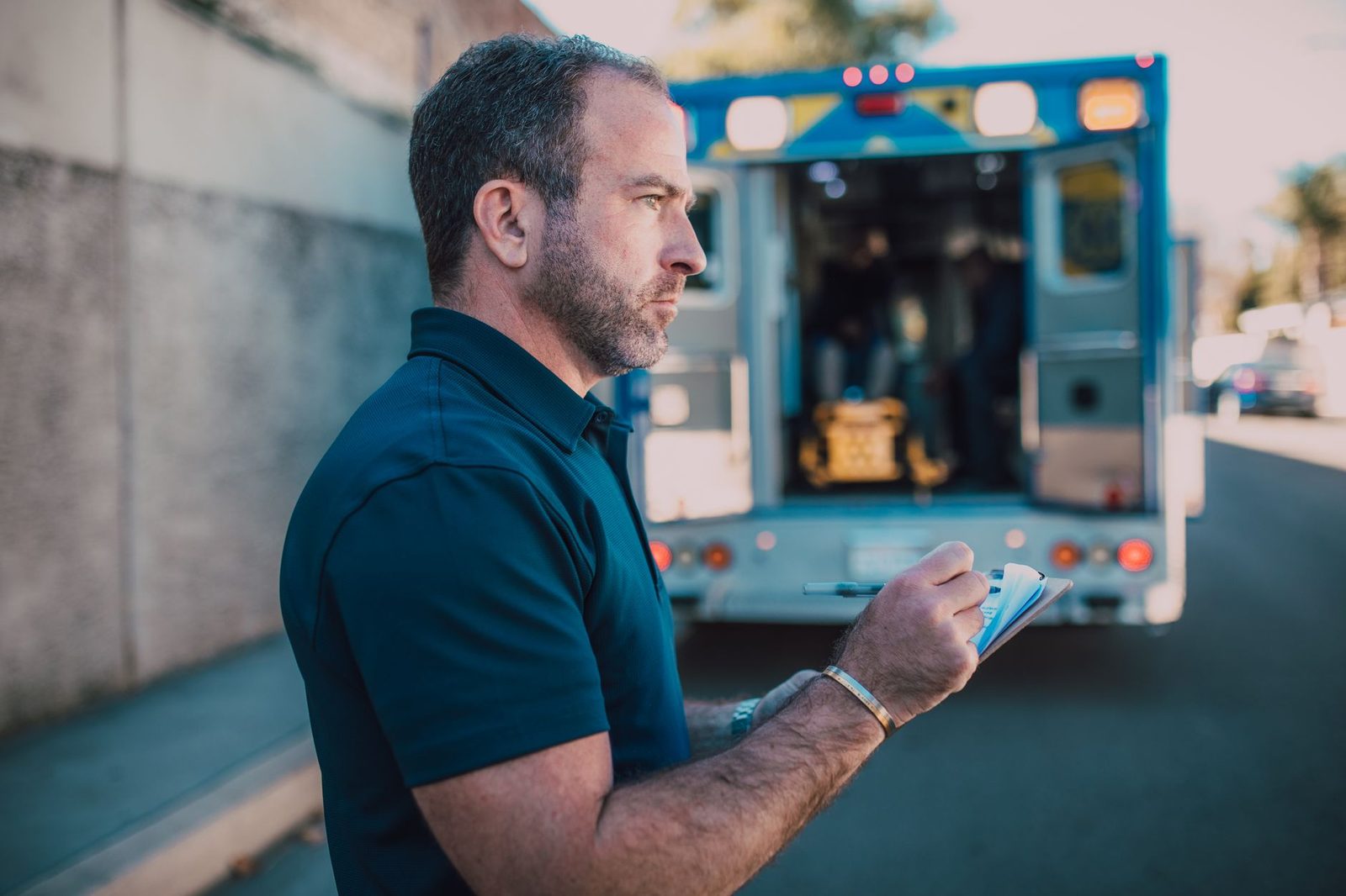 Paramedic documenting patient information beside an ambulance.