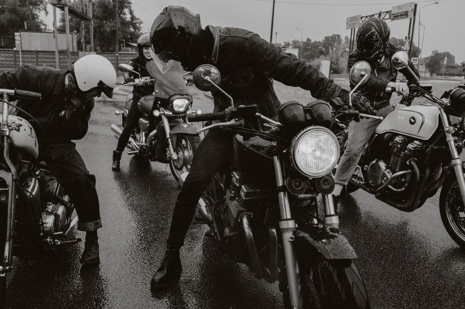 Varios motociclistas circulan juntos por una calle mojada.
