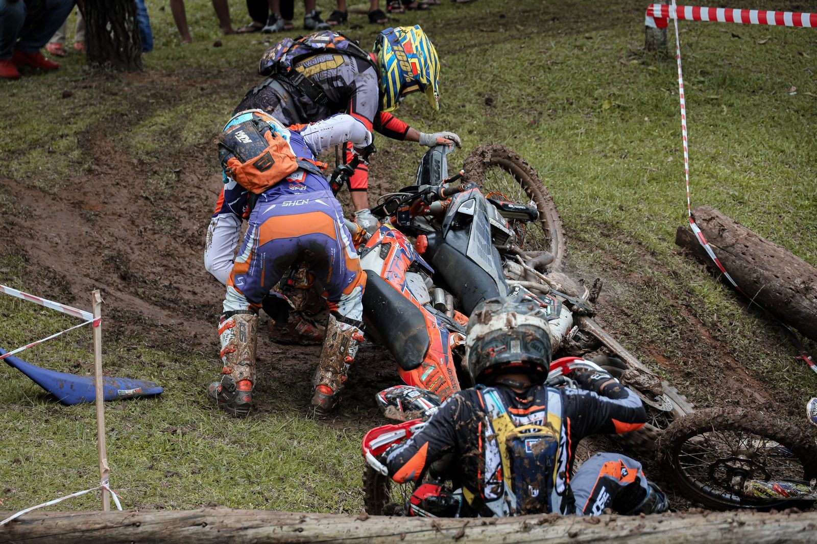 Three motorcycle riders involved in a crash on a muddy track in Bandung, Indonesia.