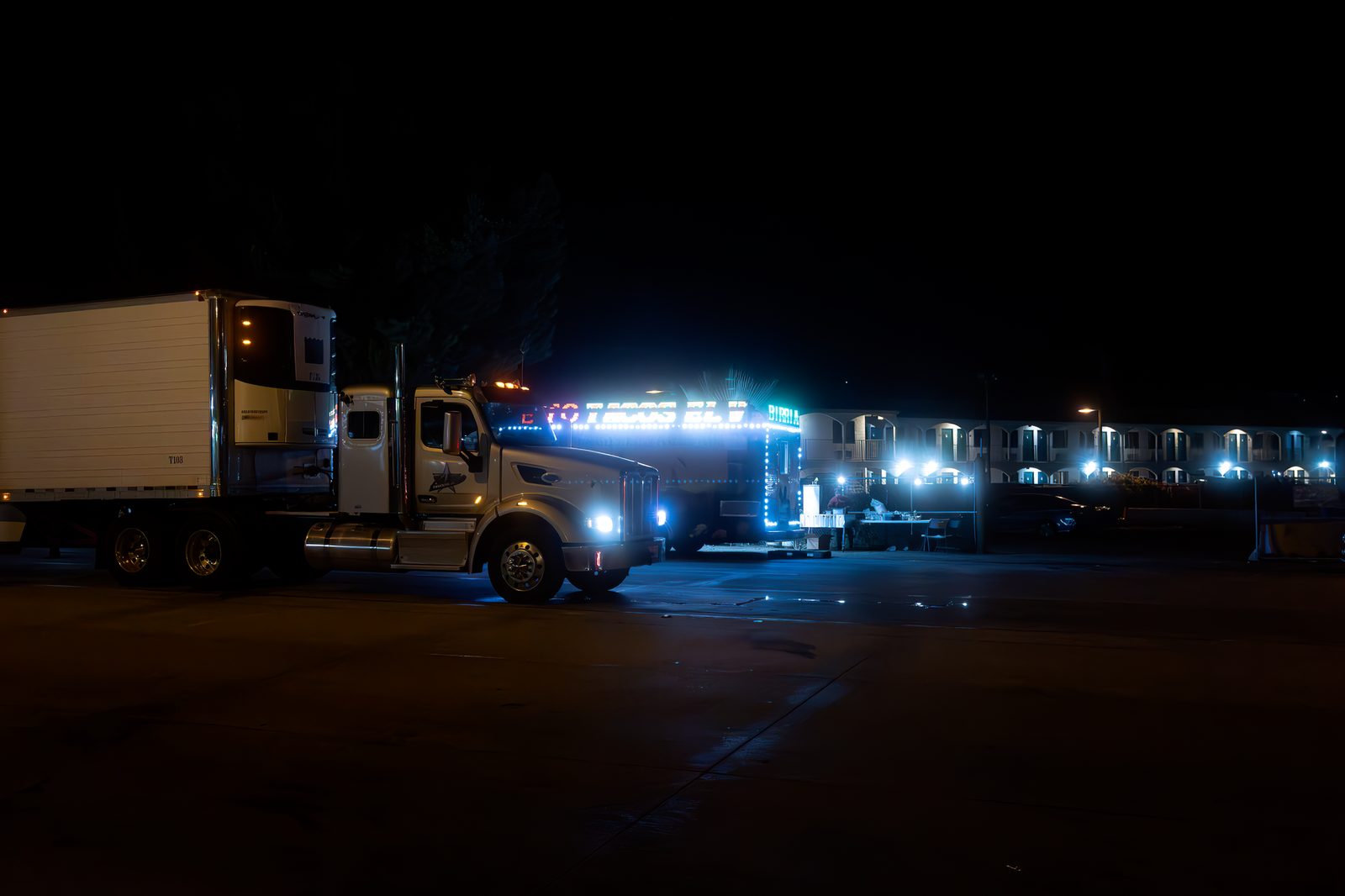 Dos camionetas con las luces encendidas estacionadas en una calle de la ciudad por la noche.