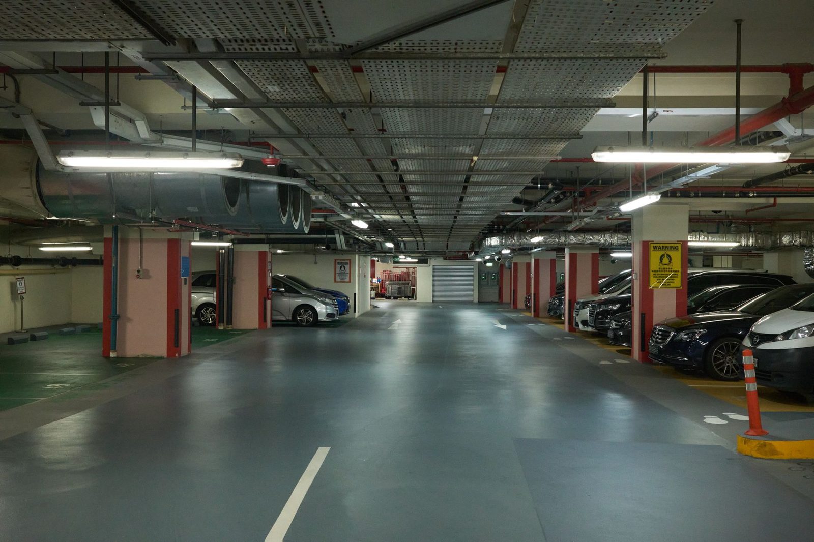 Wide view of a dimly lit underground parking garage with rows of modern cars.