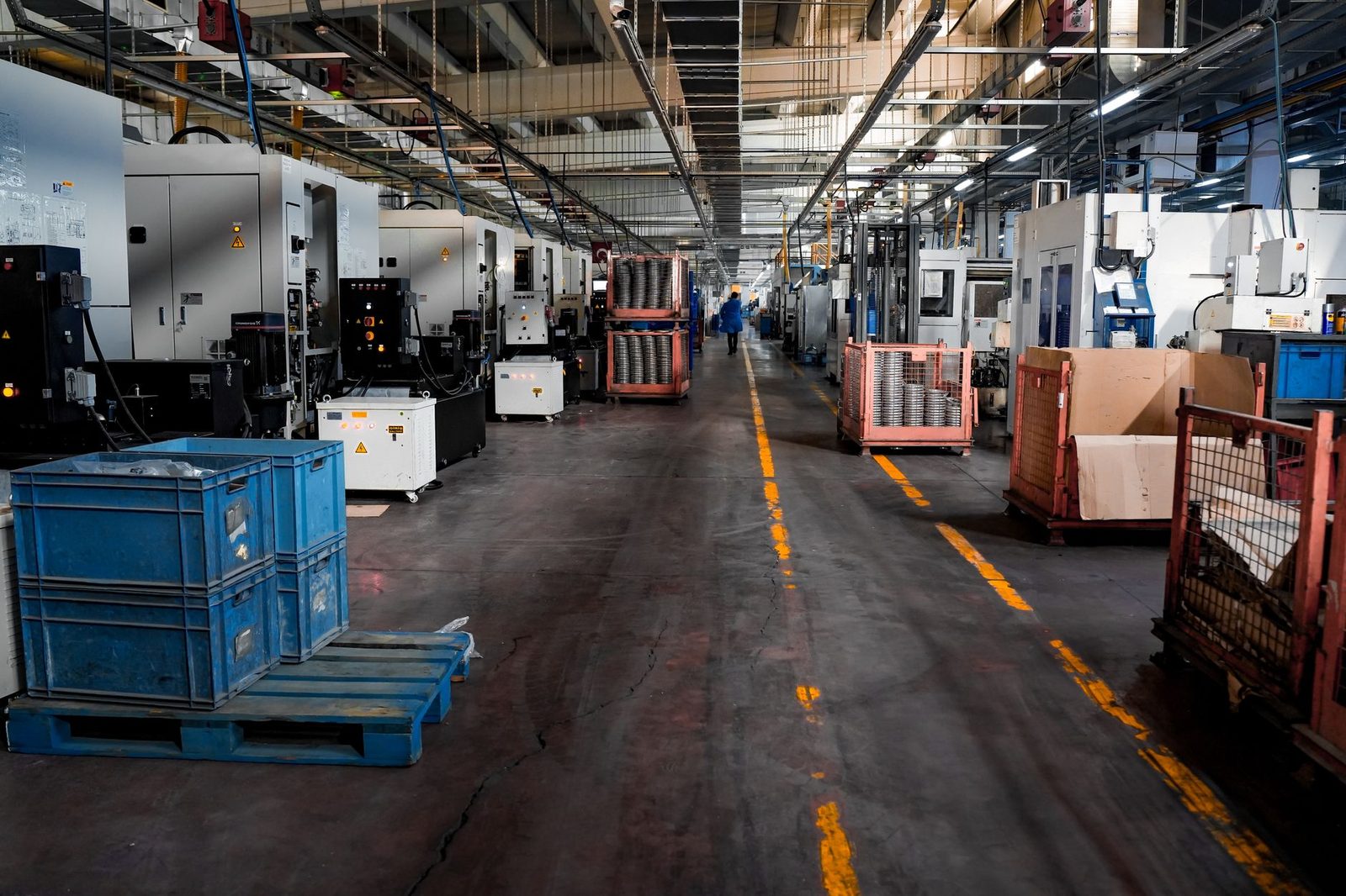 Vista amplia de una gran planta industrial con filas de maquinaria, cajas apiladas y estaciones de trabajo organizadas.