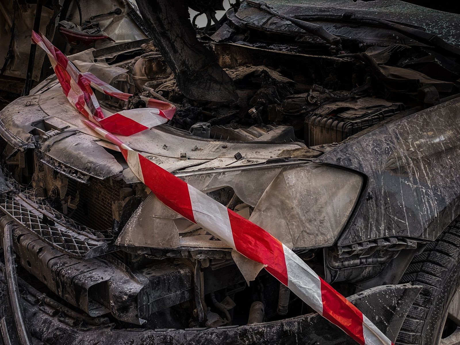 Close-up of a crashed car wrapped in red and white safety tape.