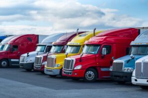 A line of trucks at a truck stop. Who is liable if an unsecure truck load causes an acident?